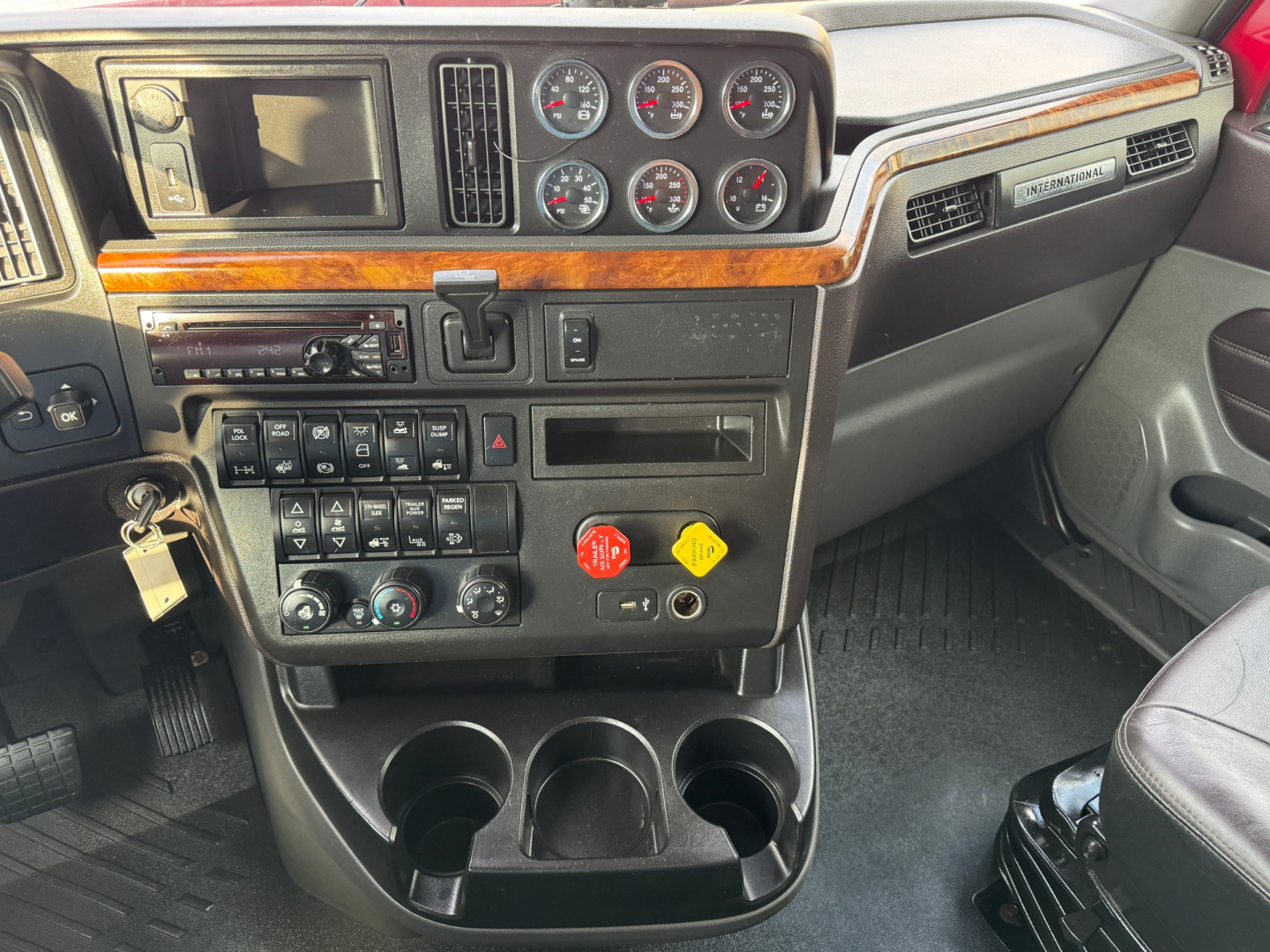 Dashboard of a 2021 International Lonestar truck with multiple gauges, control switches, wood trim, cup holders, and auxiliary buttons. Visible text includes various gauge faces and labels.