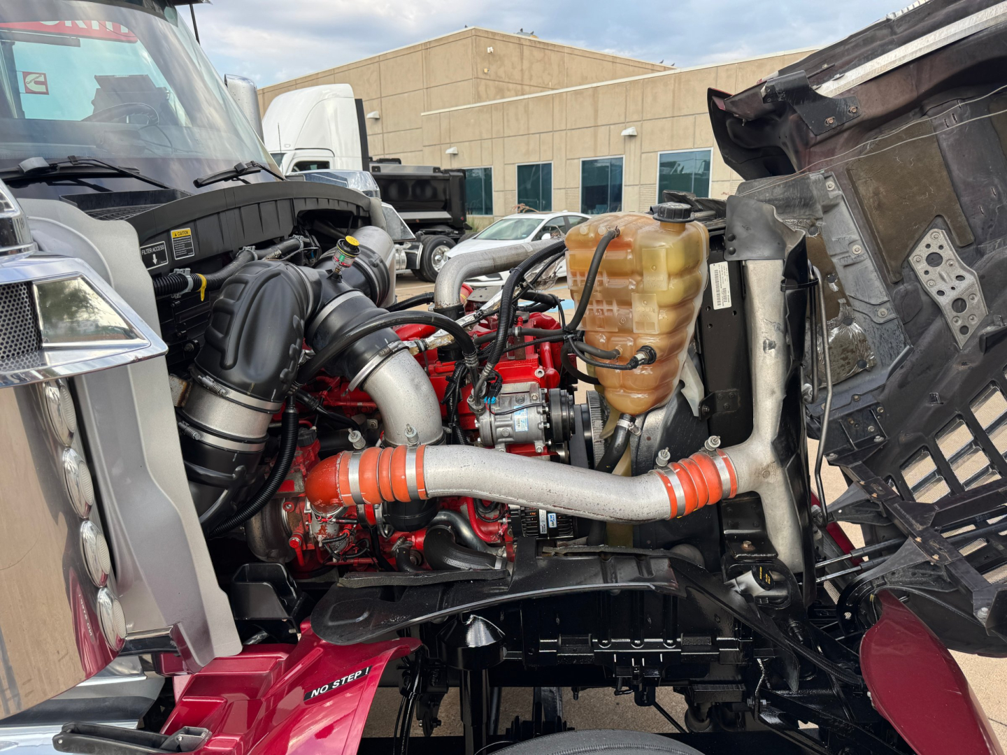 Engine bay of a 2021 International Lonestar sleeper showing a red engine with hoses, coolant reservoir, and surrounding components.