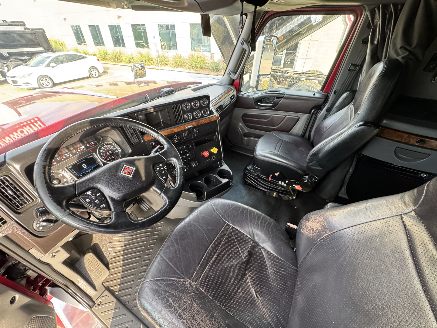 Interior of a truck cabin showing steering wheel, dashboard, and driver seat of a 2021 International Lonestar.