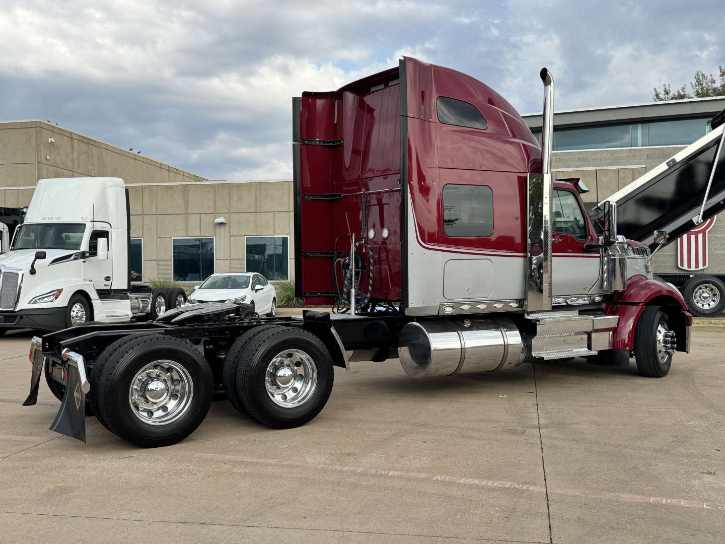 Truck chassis with maroon sleeper cab showing rear axles and fuel tanks.