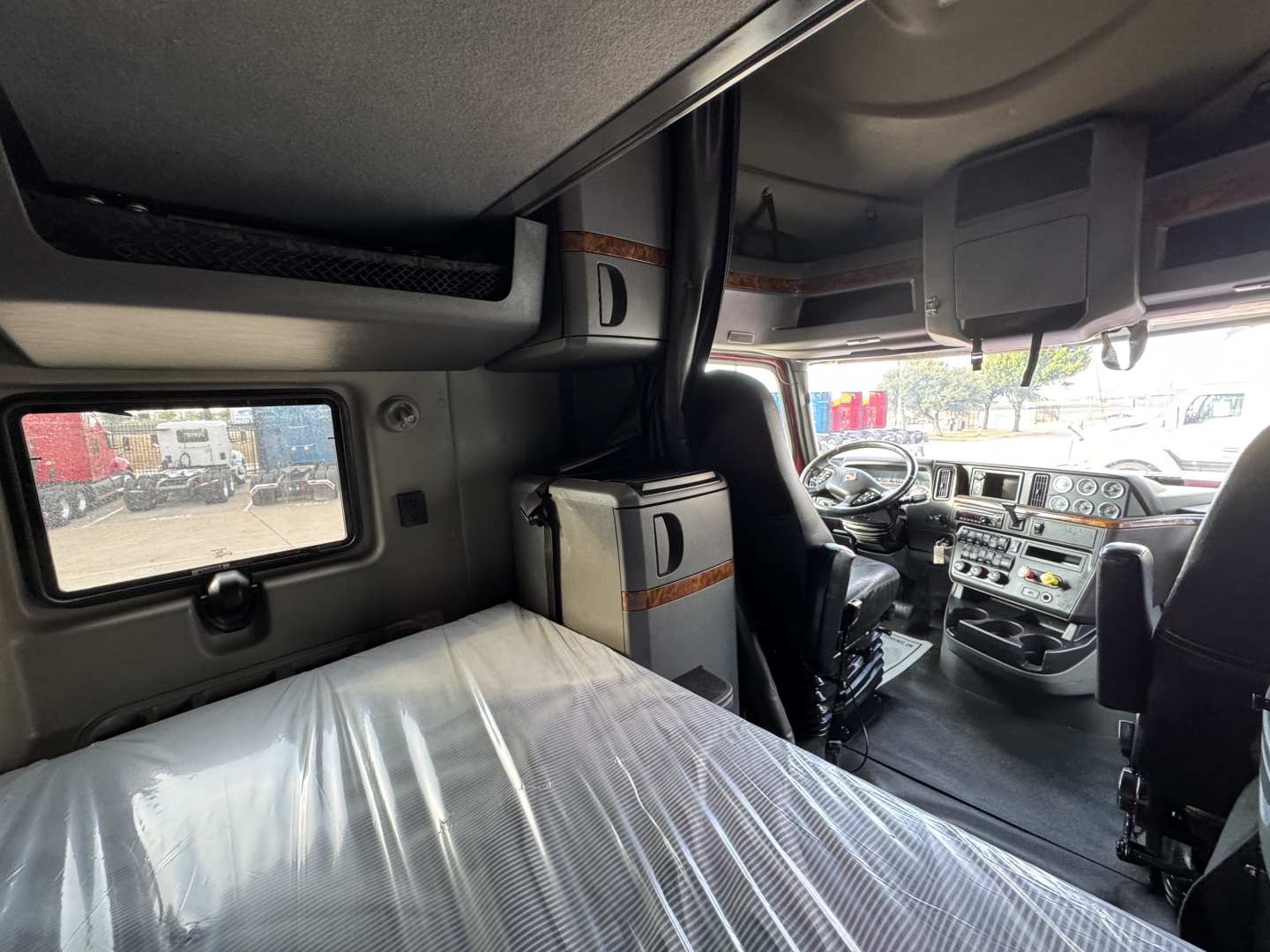 Cab interior of a 2021 International Lonestar sleeper cab showing driver's seat and dashboard with bunk area.