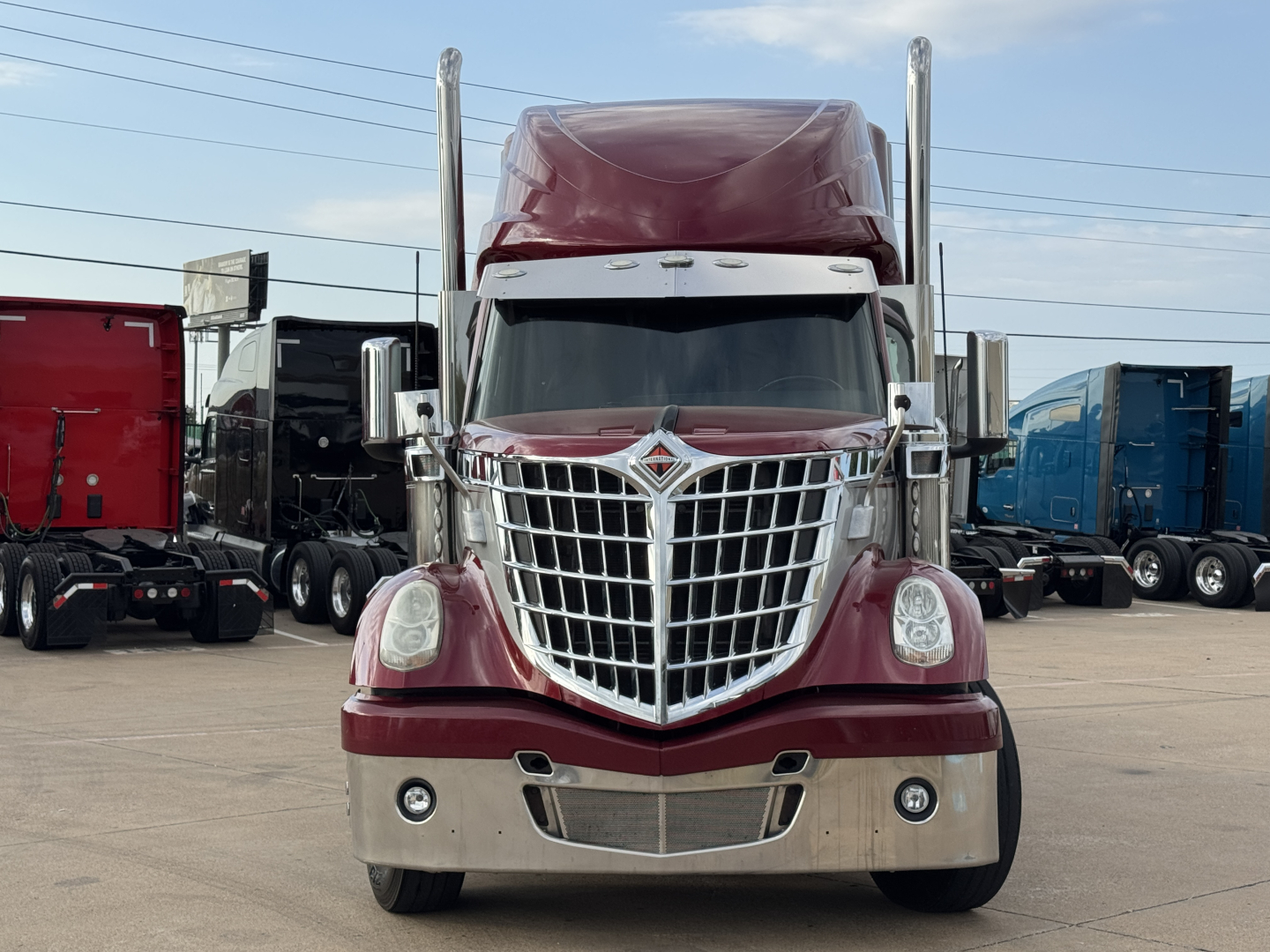 Truck front view of a maroon 2021 International Lonestar sleeper with chrome grille and bumper, large badge, and high sleeper cabin.