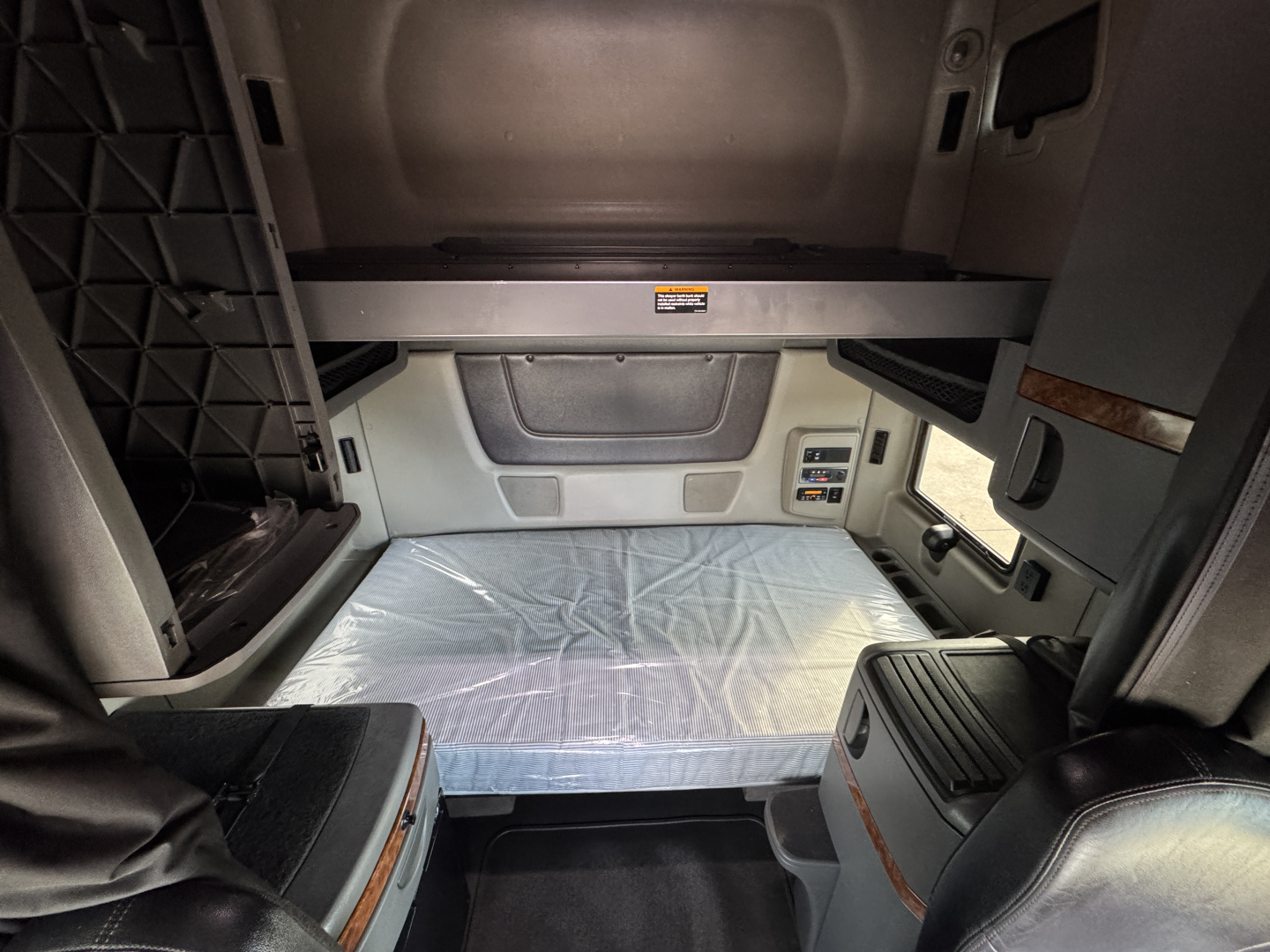 Interior cab view of a 2021 International Lonestar sleeper cab showing seating area and dashboard panels with storage compartments.