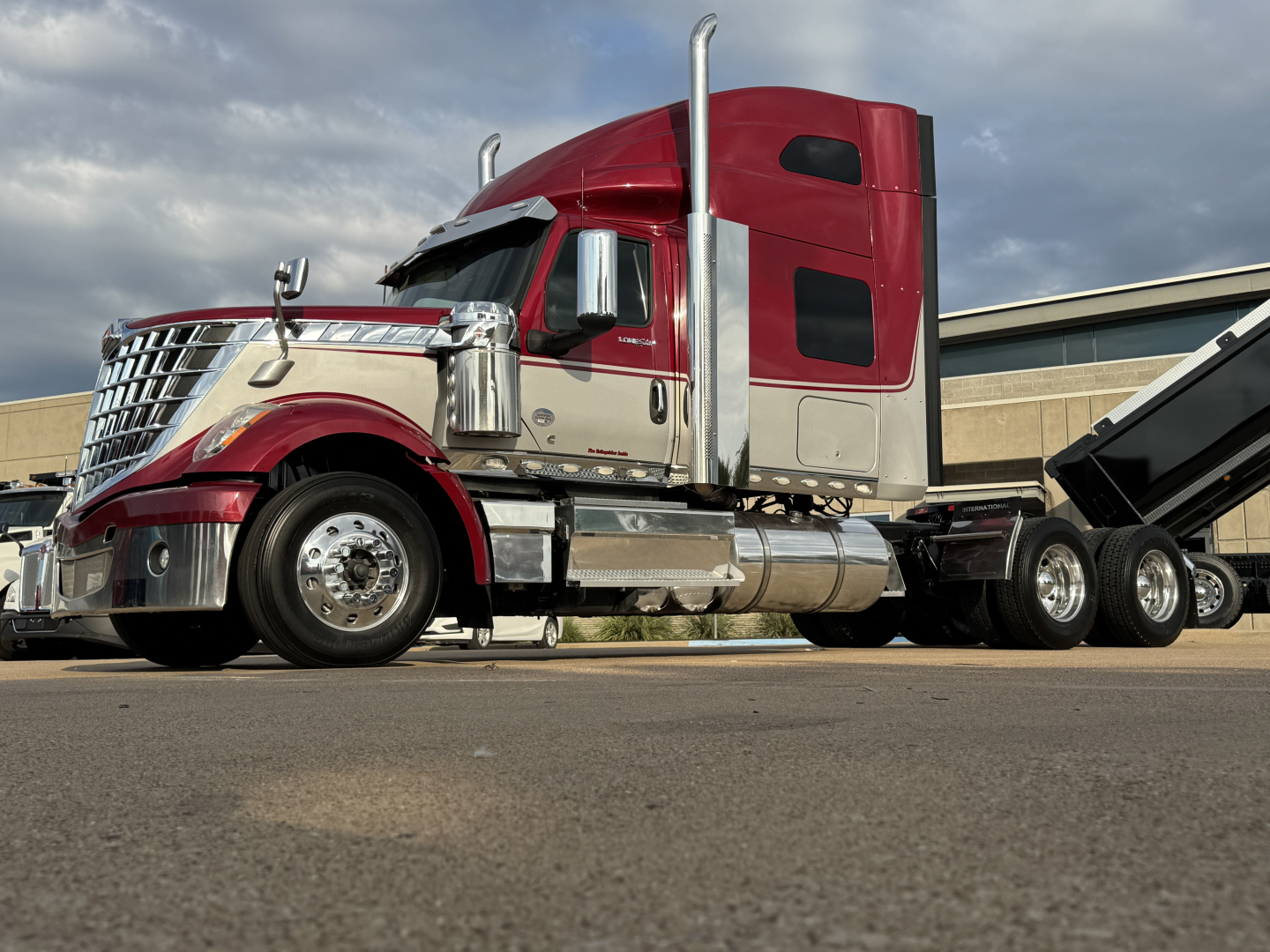 Truck cab and dump trailer from a 2021 International Lonestar sleeper configuration, red and tan color with chrome exhaust stacks and dual rear axles.