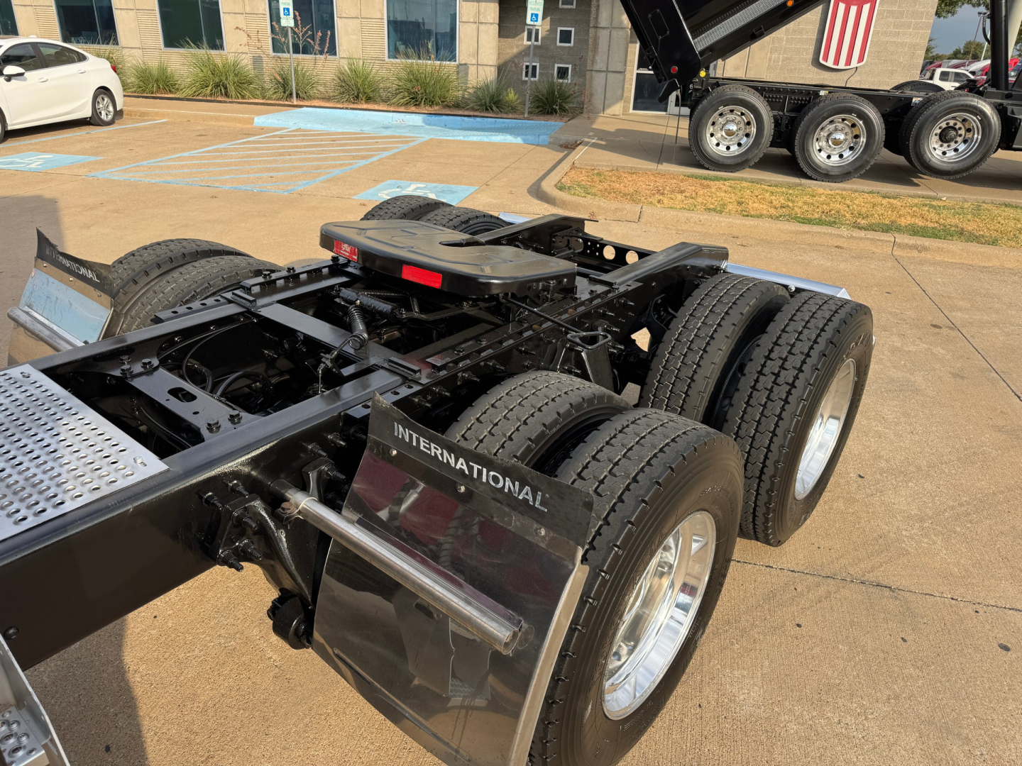 Tractor-trailer chassis and fifth-wheel area of a used 2021 International Lonestar tractor showing rear dual tire setup and International-branded mudguard.