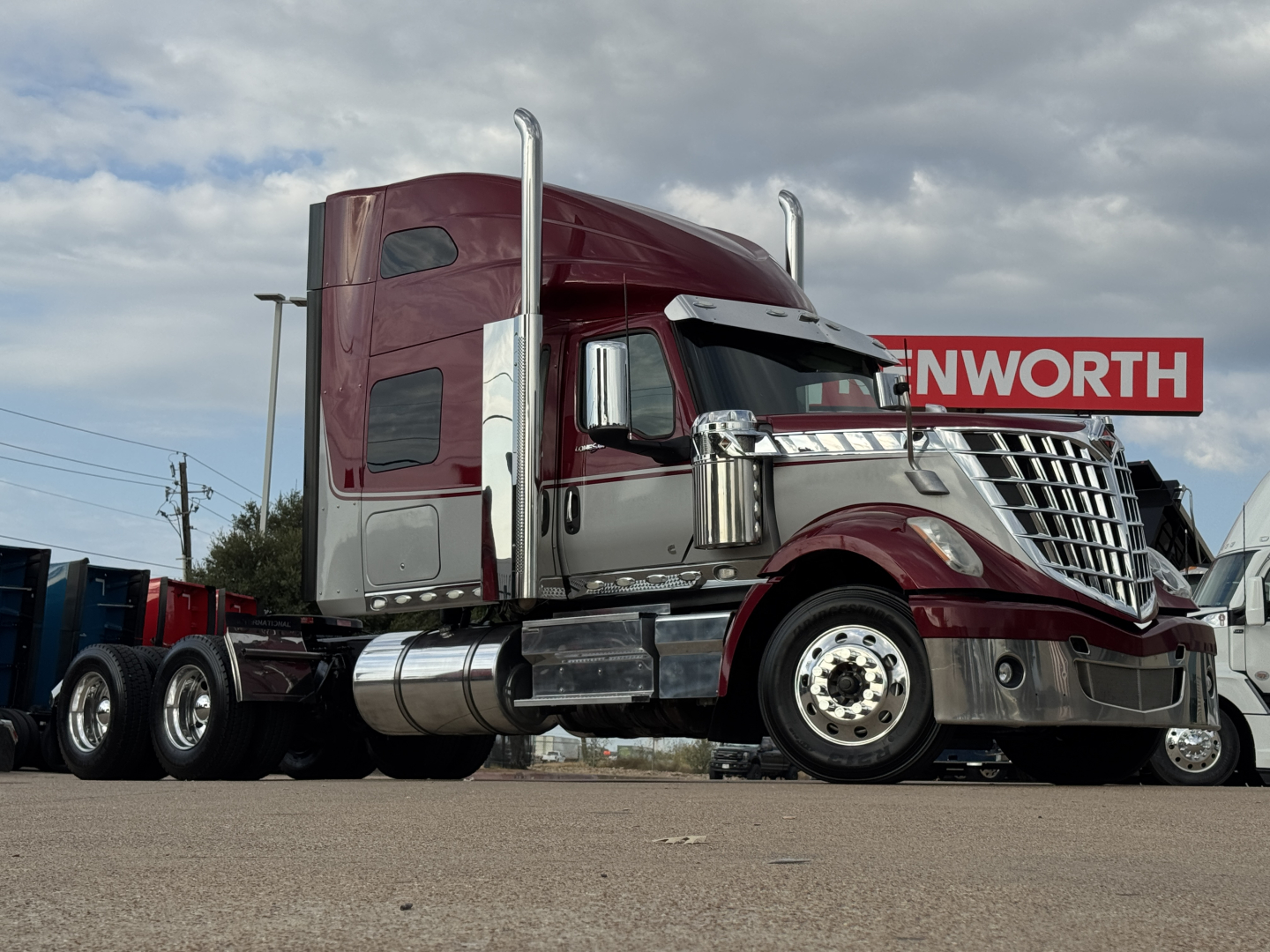 International Lonestar truck cab and front section in maroon and chrome with sleeper, diesel tanks, and dual exhaust stacks.