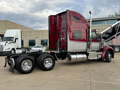 Truck chassis with maroon sleeper cab showing rear axles and fuel tanks.
