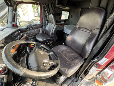 Cab interior of a 2021 International Lonestar truck showing steering wheel, driver's seat, dashboard controls, and sleeper area.