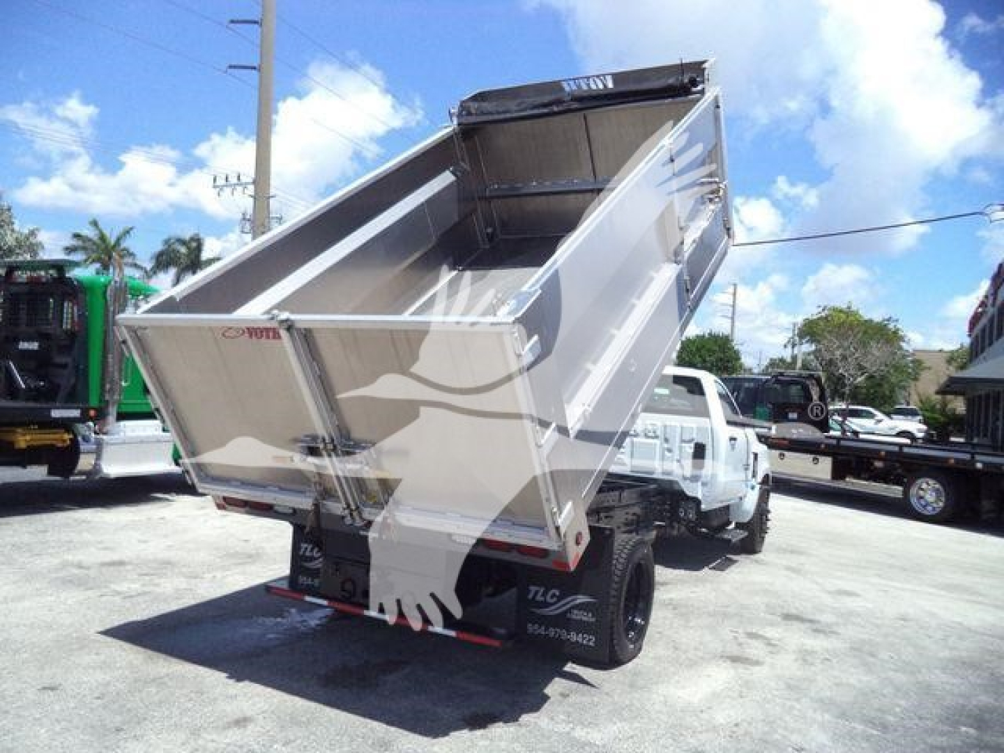 Back view of a 2023 Chevrolet Silverado 6500HD dump truck with its bed raised, showing the rear tailgate and hydraulic components.