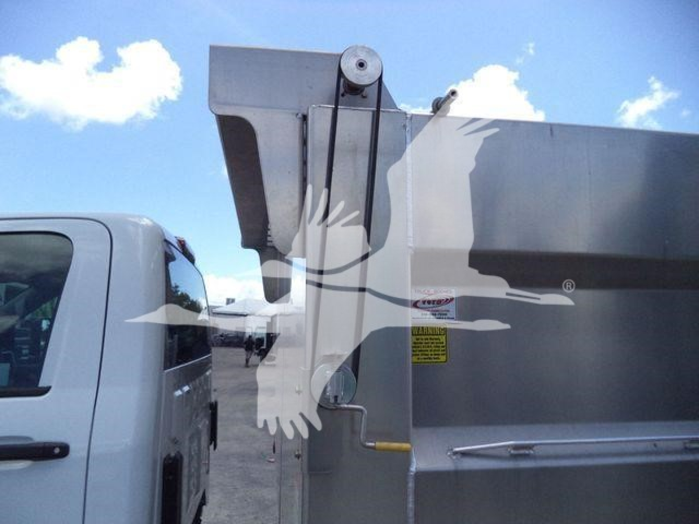 Dump truck rear with hydraulic dump bed and hoist hardware visible.