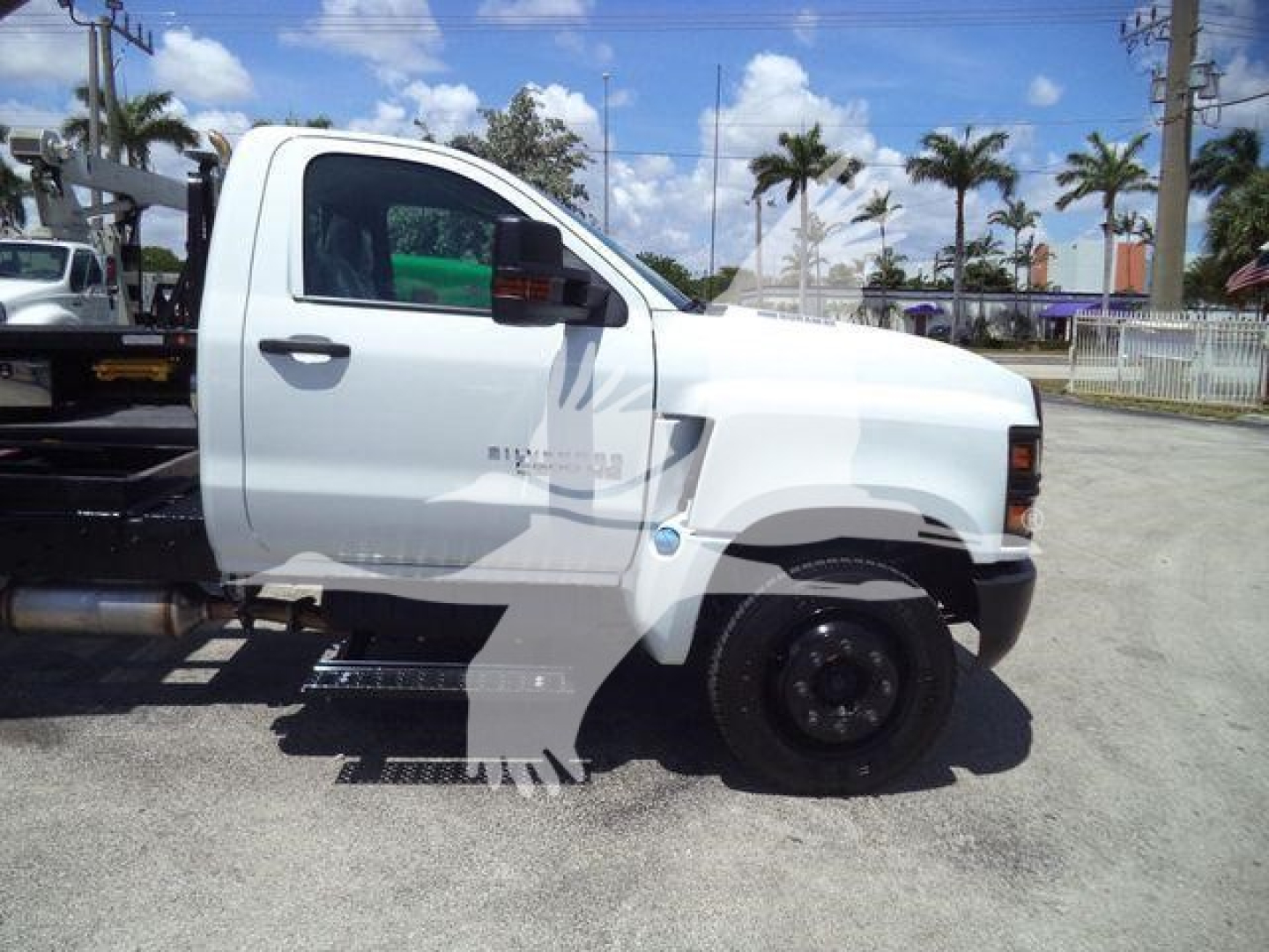 Front/side view of a white 2023 Chevrolet Silverado 6500HD dump truck cab with step side, black wheels, and stock number 6500ALUMDMP visible.