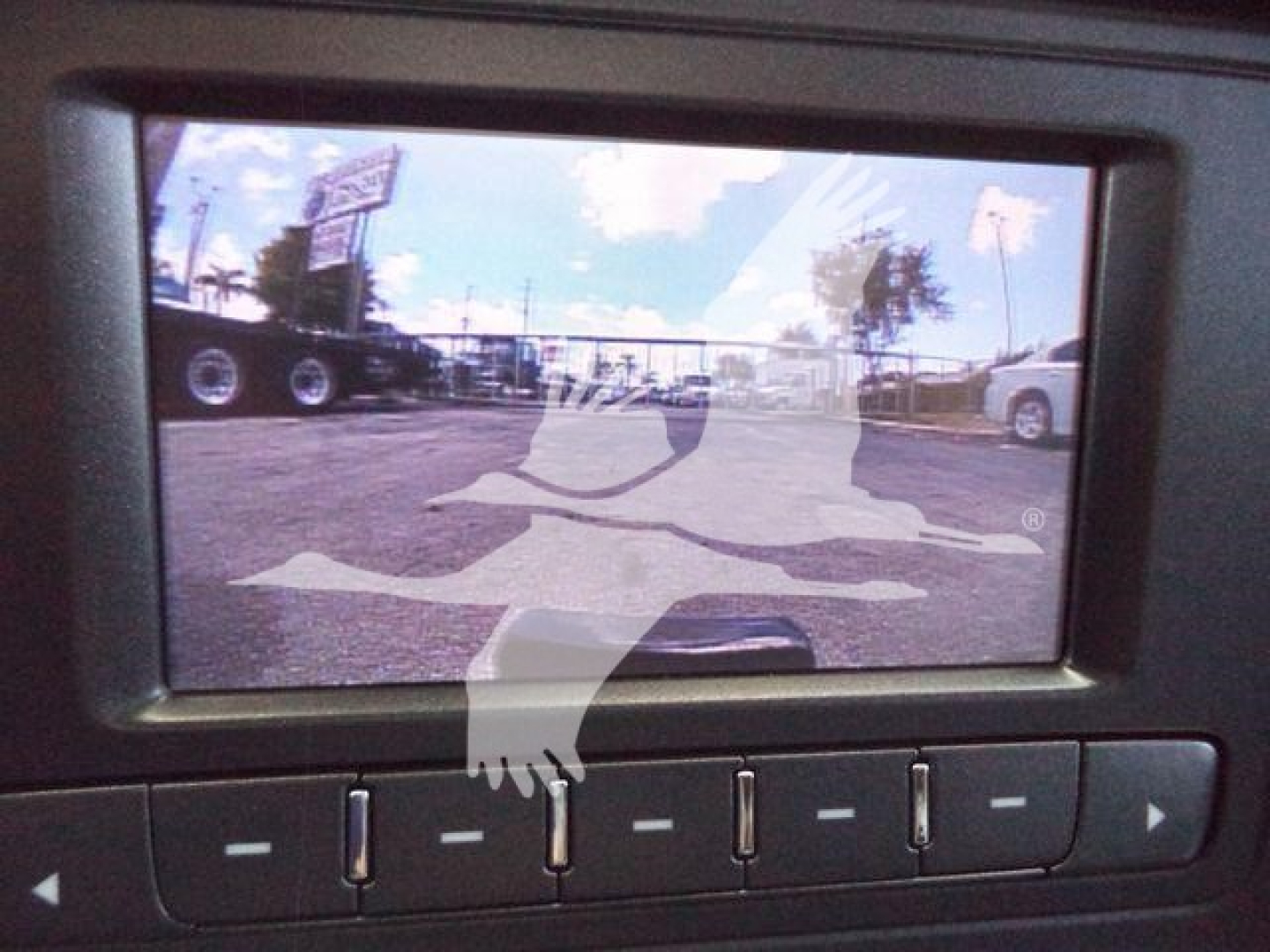 Chevrolet Silverado 6500HD dump truck dashboard screen showing a rearview/backup camera display with a parking lot and trailers in view.