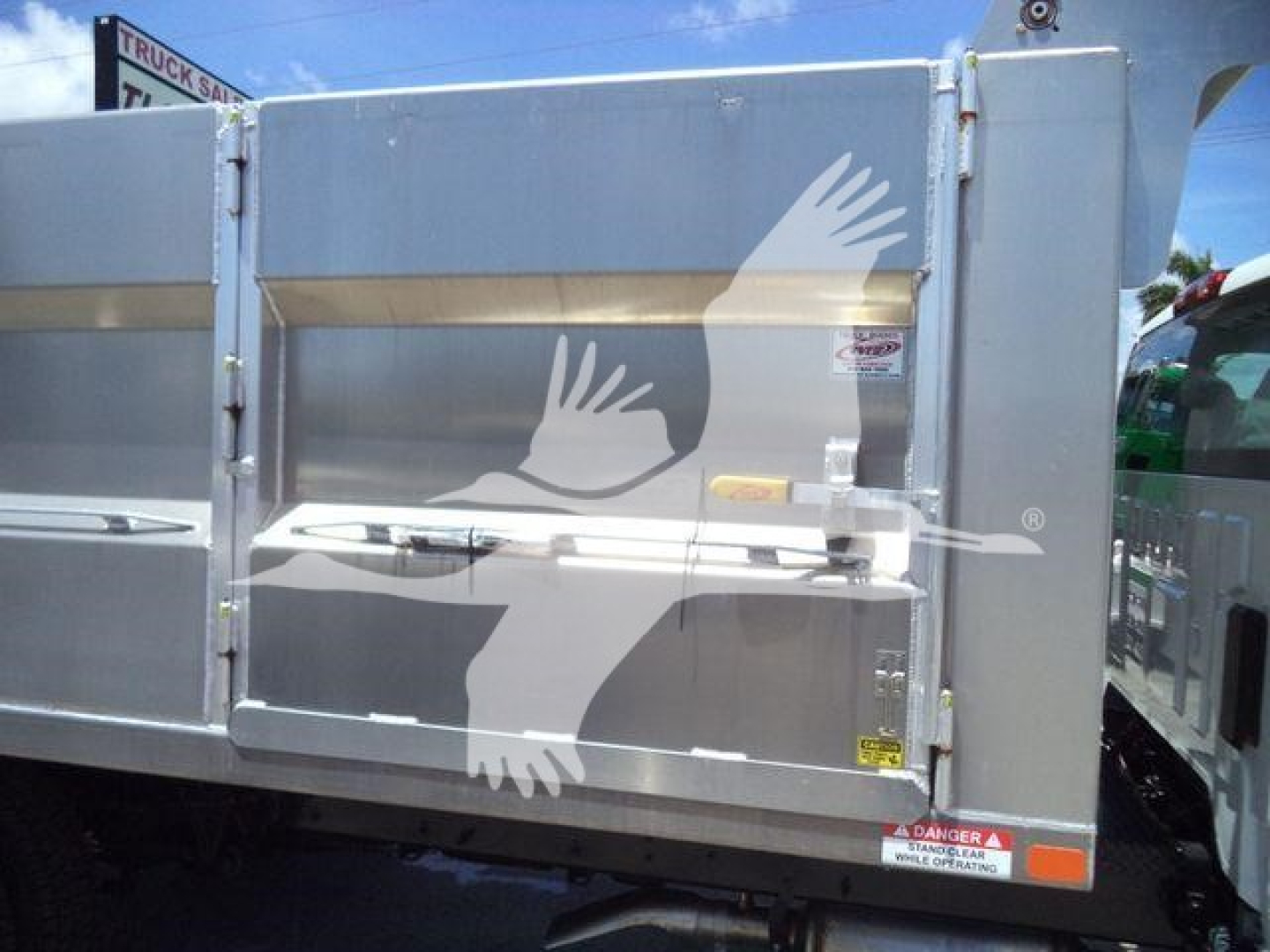 Truck dump body side doors with warning labels and reflective decals visible.