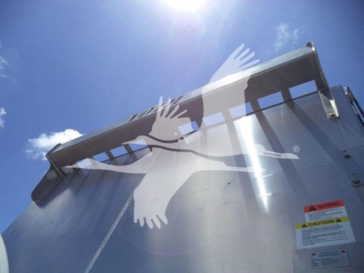 Dump truck bed side and tailgate of a 2023 Chevrolet Silverado 6500HD with a warning sticker visible and a reflection of a bright sky.
