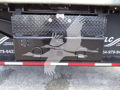 Truck bed toolbox mounted on a Chevrolet Silverado 6500HD dump truck showing a diamond plate toolbox with latches and a cracked open area.