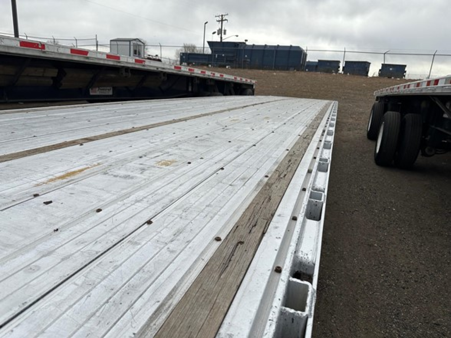 All-aluminum Trail King TK drop deck trailer bed showing metal decking and edge with wheel undercarriage visible at rear.