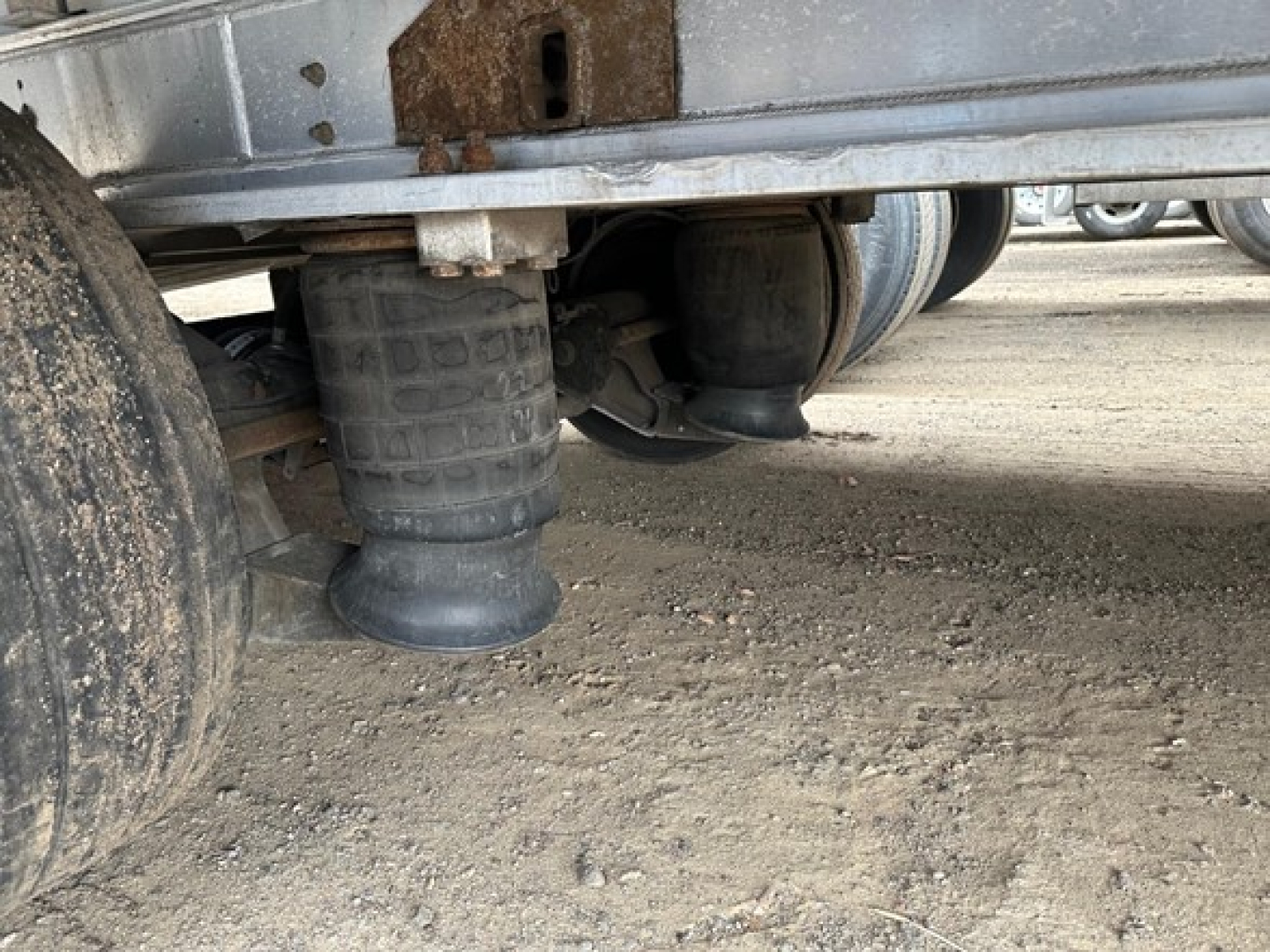 Air suspension air bag under trailer with cylindrical air spring and undercarriage components visible.