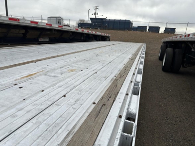 All-aluminum Trail King TK drop deck trailer bed showing metal decking and edge with wheel undercarriage visible at rear.