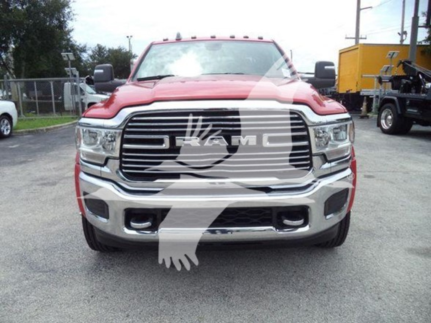 Front view of a red RAM pickup truck with large grille and RAM emblem, chrome bumper, and headlights.