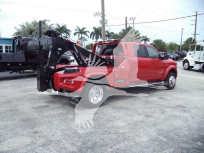 Ram pickup truck with a front-mounted industrial winch and grapple attachment in a dealership lot.