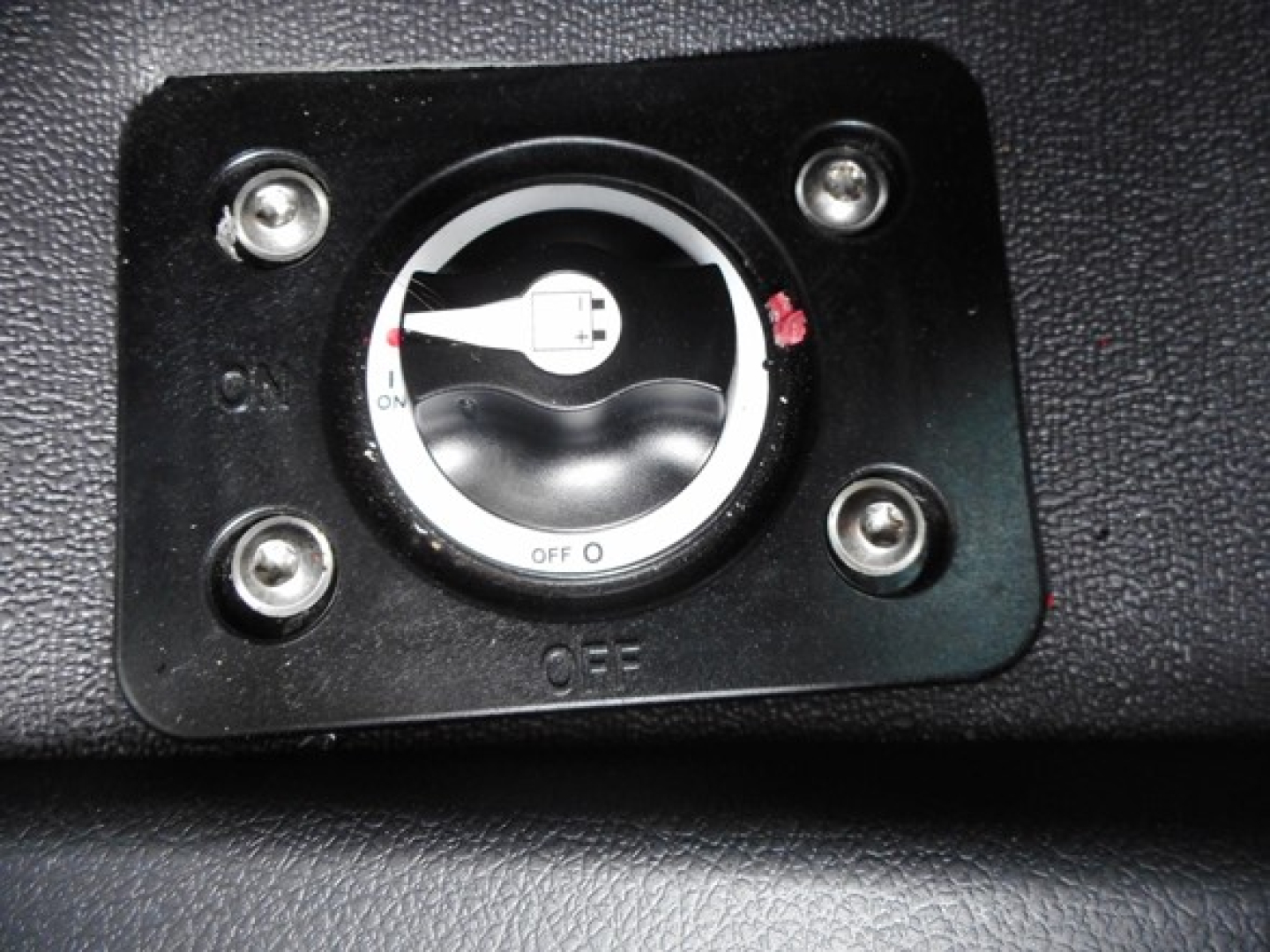 Dialed switch in dash with OFF position and surrounding screws; circular knob with white center and black outer ring.