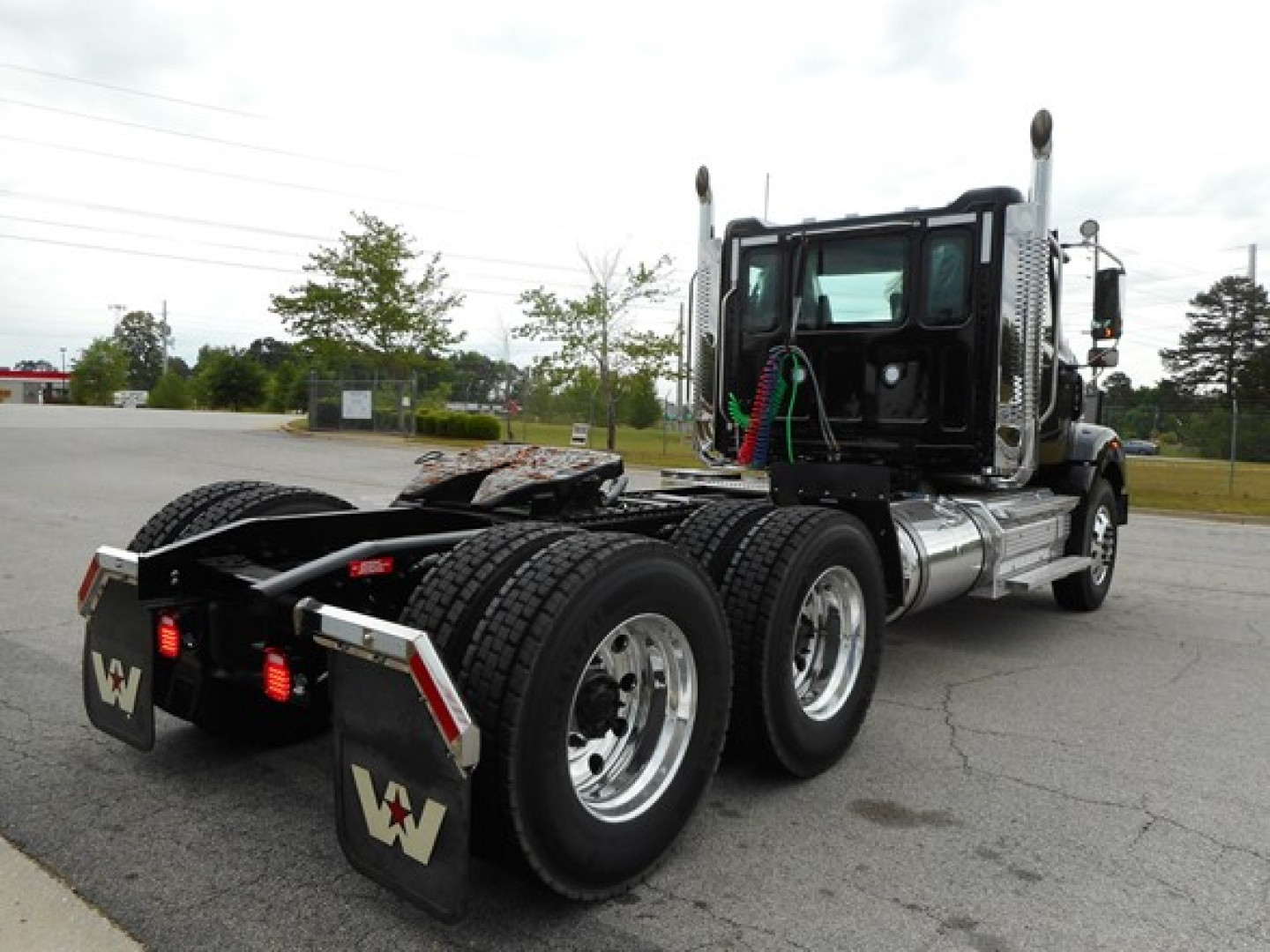 Truck chassis and cab of a new 2026 Western Star 49X Day Cab tractor showing rear wheels and fifth-wheel area with spare mudflaps branded Western Star.