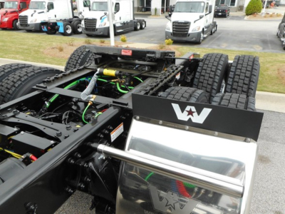 Tractor truck chassis with exposed drivetrain and green hoses; Western Star logo on platform guard; front cab missing, showing fifth wheel and frame.
