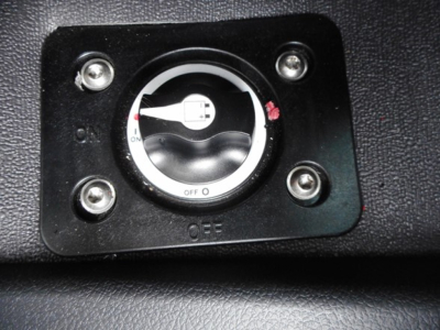 Dialed switch in dash with OFF position and surrounding screws; circular knob with white center and black outer ring.