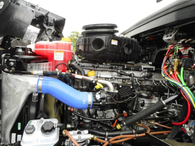 West Star 49X engine bay showing blue coolant hose and various lines, reservoirs, and wiring harnesses.