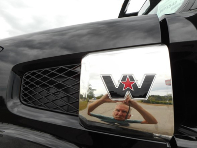 Front left grille and chrome emblem with star logo on a Western Star 49X truck hood reflection visible in bumper chrome