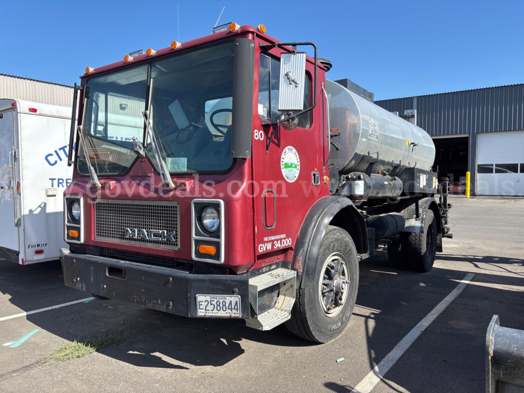 Tank truck front-left view showing Mack MR685P chassis and cylindrical tanker with capacity markings.