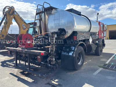 Tank truck with front-mounted crane and chrome tank showing ‘ONE STOP WASTE SERVICES’ text, rear view with hydraulic hoses and equipment, Mack chassis partially visible.