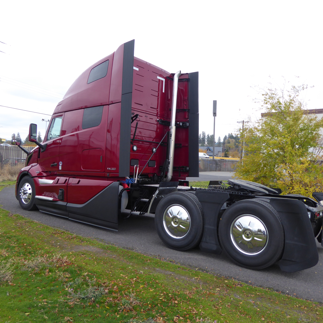 Volvo VNL64T860 truck cab side view showing sleeper, red exterior, large fuel tanks, and dual rear axles with chrome wheels.