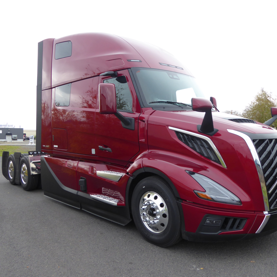 Volvo VNL64T860 truck cab and front wheel showing sleek red exterior and sleeper cab