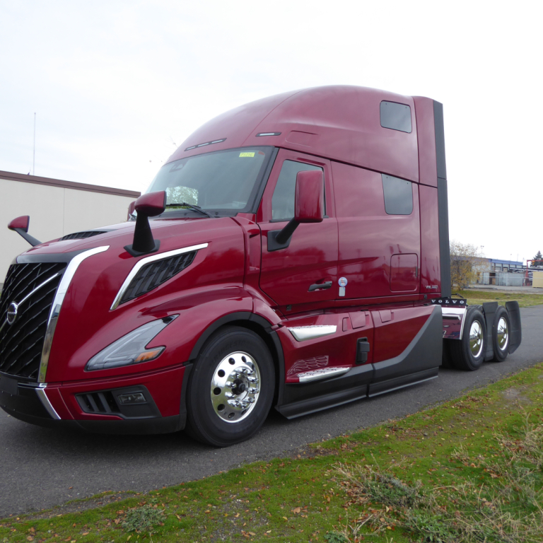 Volvo VNL64T860 long-nose sleeper tractor in deep red with chromed grille, side mirrors, and dual rear axles; view shows cab front-left profile.