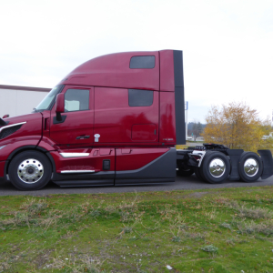 Volvo VNL64T860 highway tractor side view showing sleeper cab, maroon color, chrome fuel tanks, and dual rear axles.