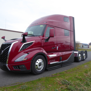 Volvo VNL64T860 long-nose sleeper tractor in deep red with chromed grille, side mirrors, and dual rear axles; view shows cab front-left profile.