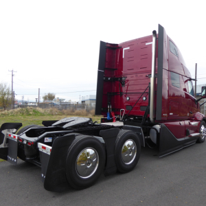 Volvo VNL64T860 truck tractor in red sleeper cab, rear view showing dual rear axles and fifth-wheel hitch.