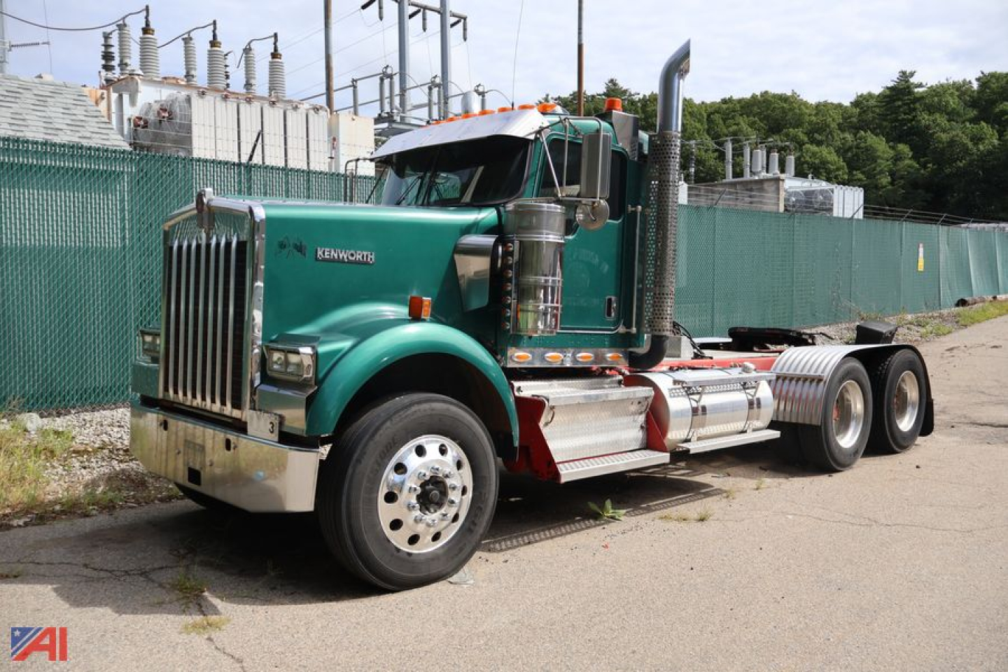 Kenworth W9 Series conventional daycab tractor shown in green with chrome fuel tanks and exhaust stacks; front grille and Kenworth emblem visible.