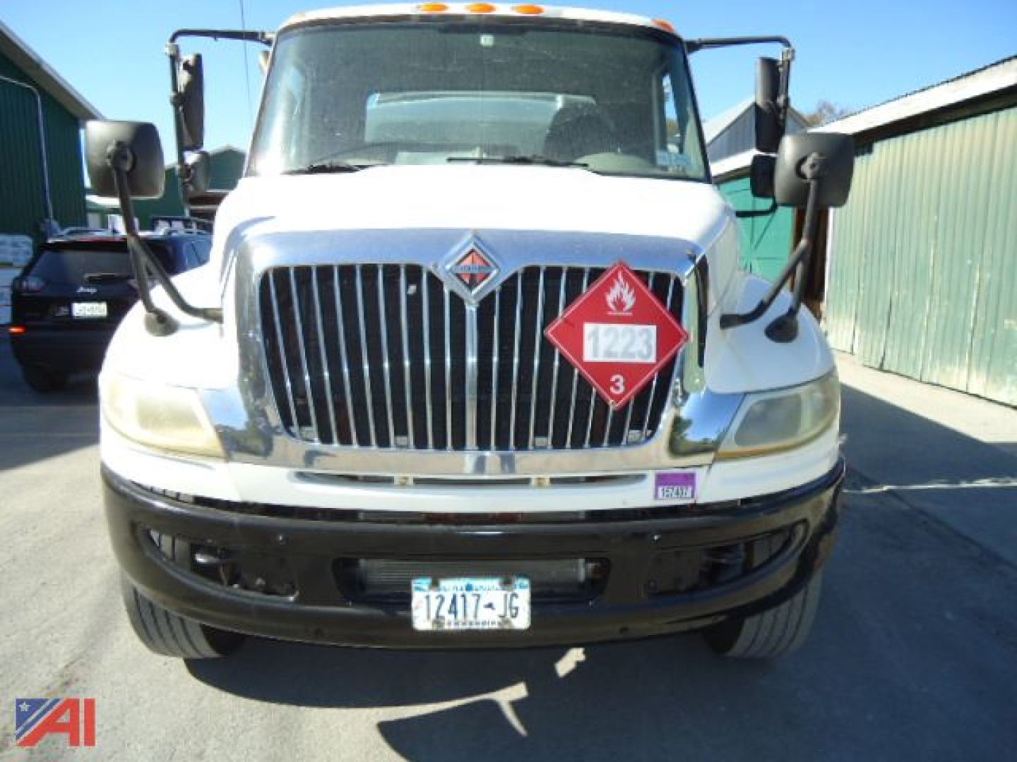 Front view of a white 2012 International MA025 DuraStar 4300 truck with a hazardous liquid placard on the grille and a black bumper.