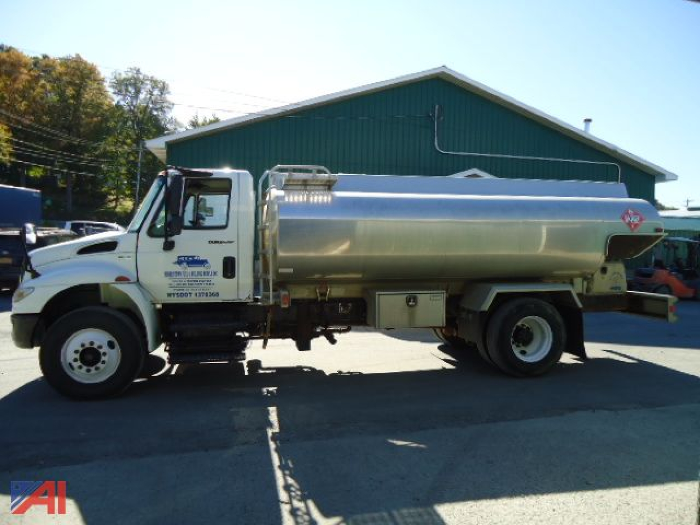 Tank truck silhouette showing 2012 International MA025 DuraStar with a cylindrical stainless steel tanker and hazard placard.