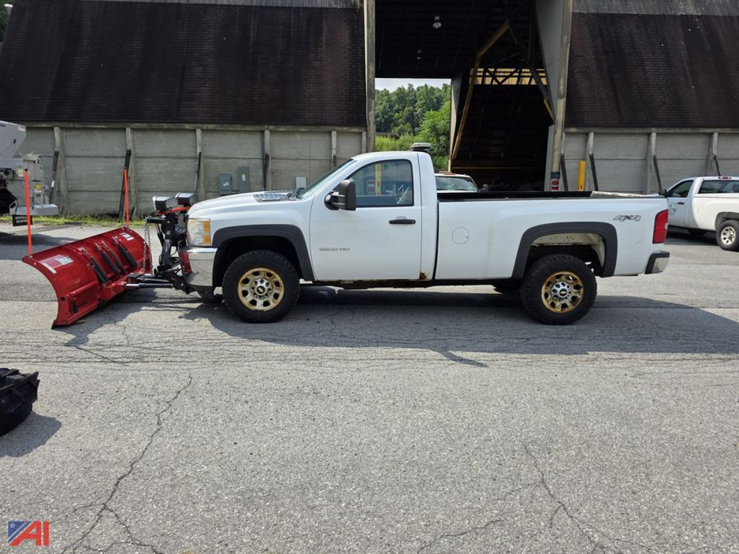 2012 Chevrolet Silverado 3500HD single cab long bed pickup with snow plow attached, white exterior, black plow mount, in a lot near a building.