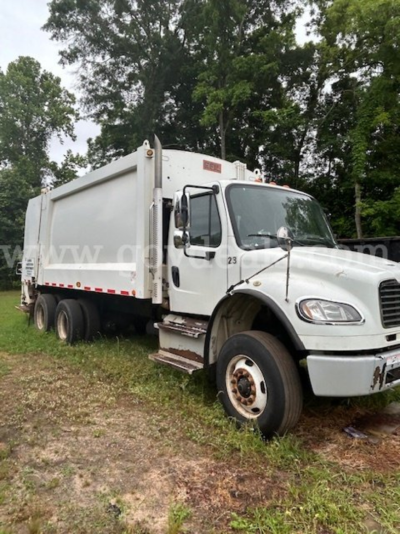 Truck cab and dump body of a 2014 Freightliner M2 106 garbage truck with white paint and dual rear axles.