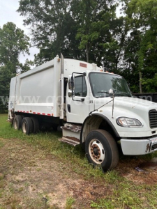 Truck cab and dump body of a 2014 Freightliner M2 106 garbage truck with white paint and dual rear axles.