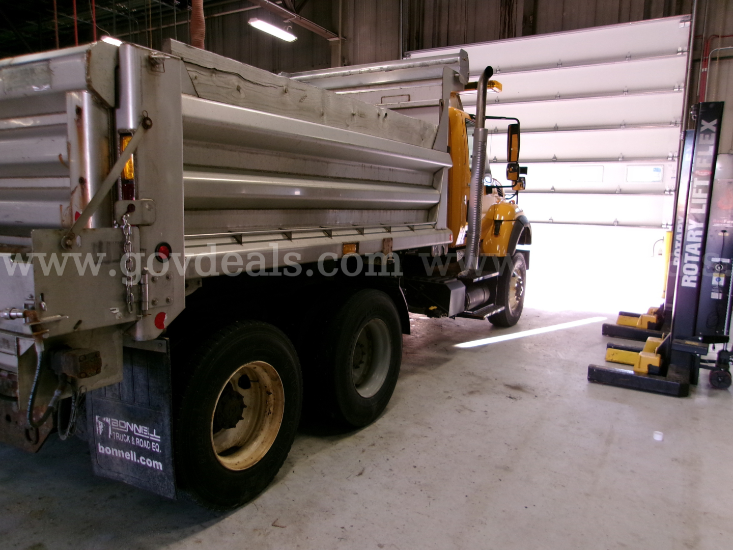 International 7400 dump truck in a shop, side view showing bed and rear wheels
