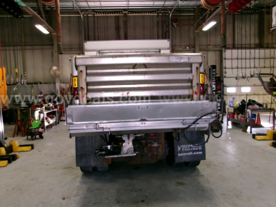 Dump truck rear showing cargo bed and bumper with lights in a workshop.