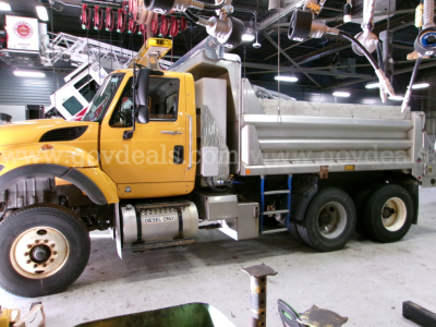 Truck dump bed in a showroom with yellow cab and gray dumping bed, International 7400, VIN 1HTWHAZT4DH369198, stock 420-464, used