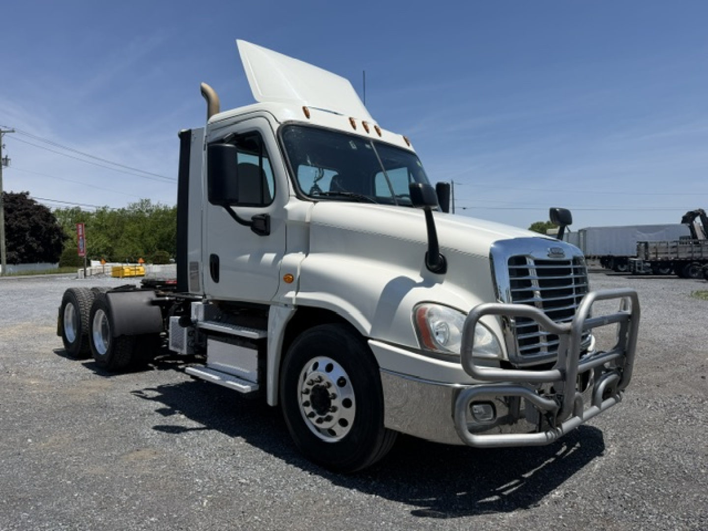 Truck cab with snow-white Freightliner Cascadia CA125DC viewed from front-right; chrome bull bar guards bumper; side steps; dual rear axles with sixth wheel; daytime; VIN plate not visible.