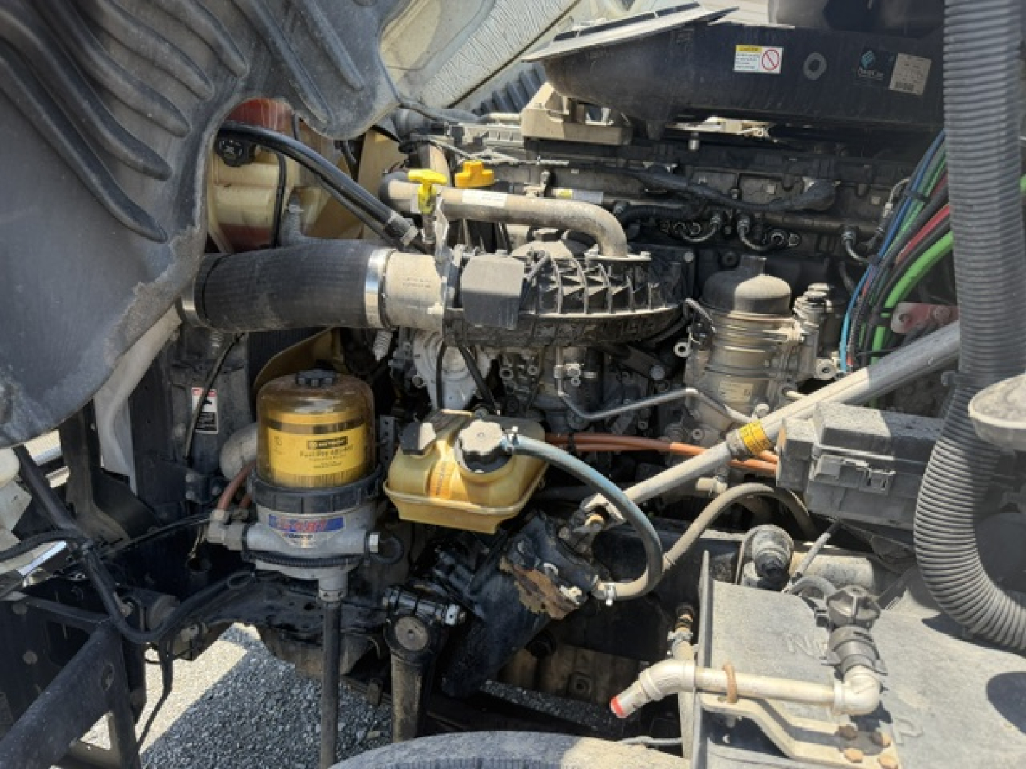 Ultrathin view of Freightliner Cascadia CA125DC engine bay showing hydraulic lines, yellow oil filter, and hoses.