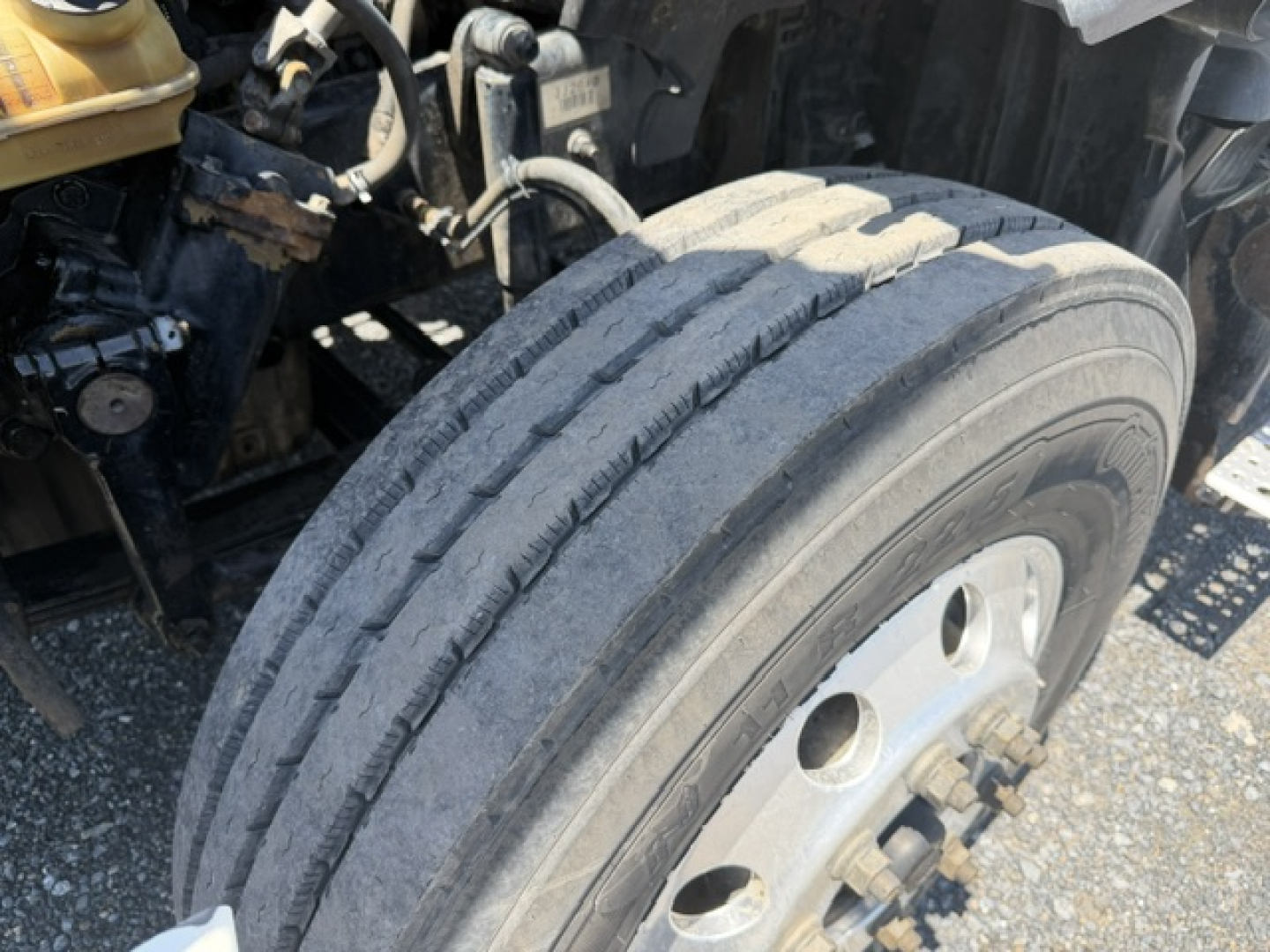 Truck front wheel and tire viewed from side showing large tread and dual rear axle area of a Freightliner Cascadia CA125DC chassis.